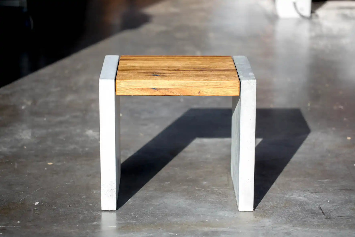 Hocker mit Sitzfläche aus Massivholz und Standfüßen aus Beton von vorne