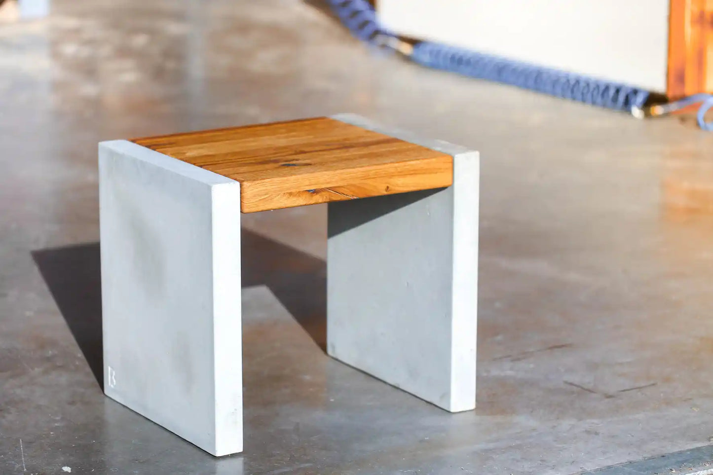 Hocker mit Sitzfläche aus Massivholz und Standfüßen aus Beton