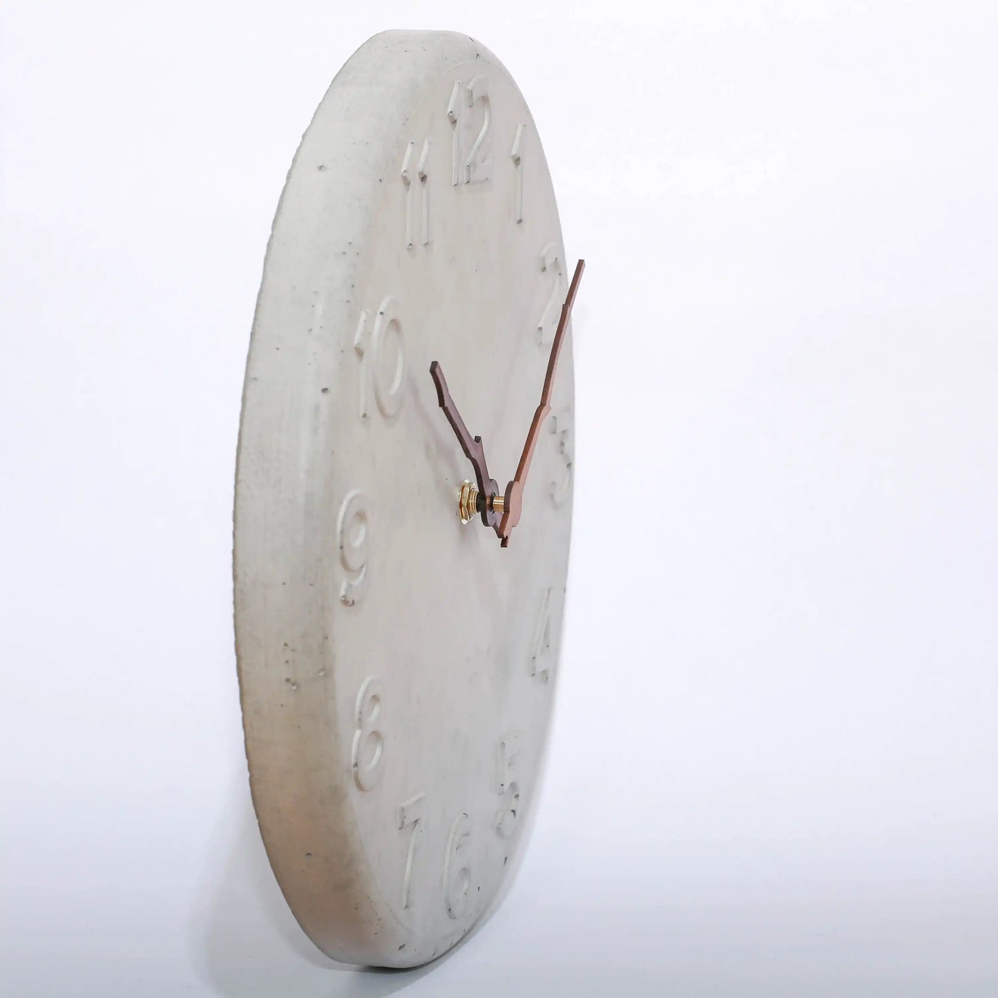 Wanduhr von der Seite aus Beton und mit Holzzeigern in Astform
