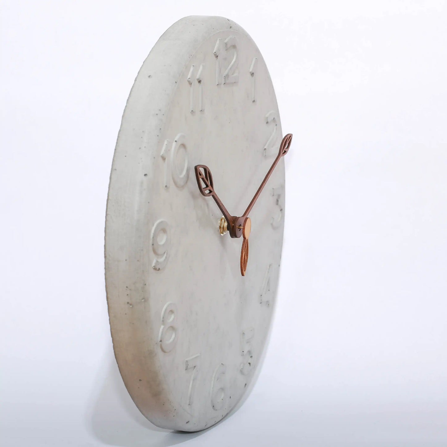 Wanduhr von der Seite aus Beton und mit Holzzeigern in Blattform