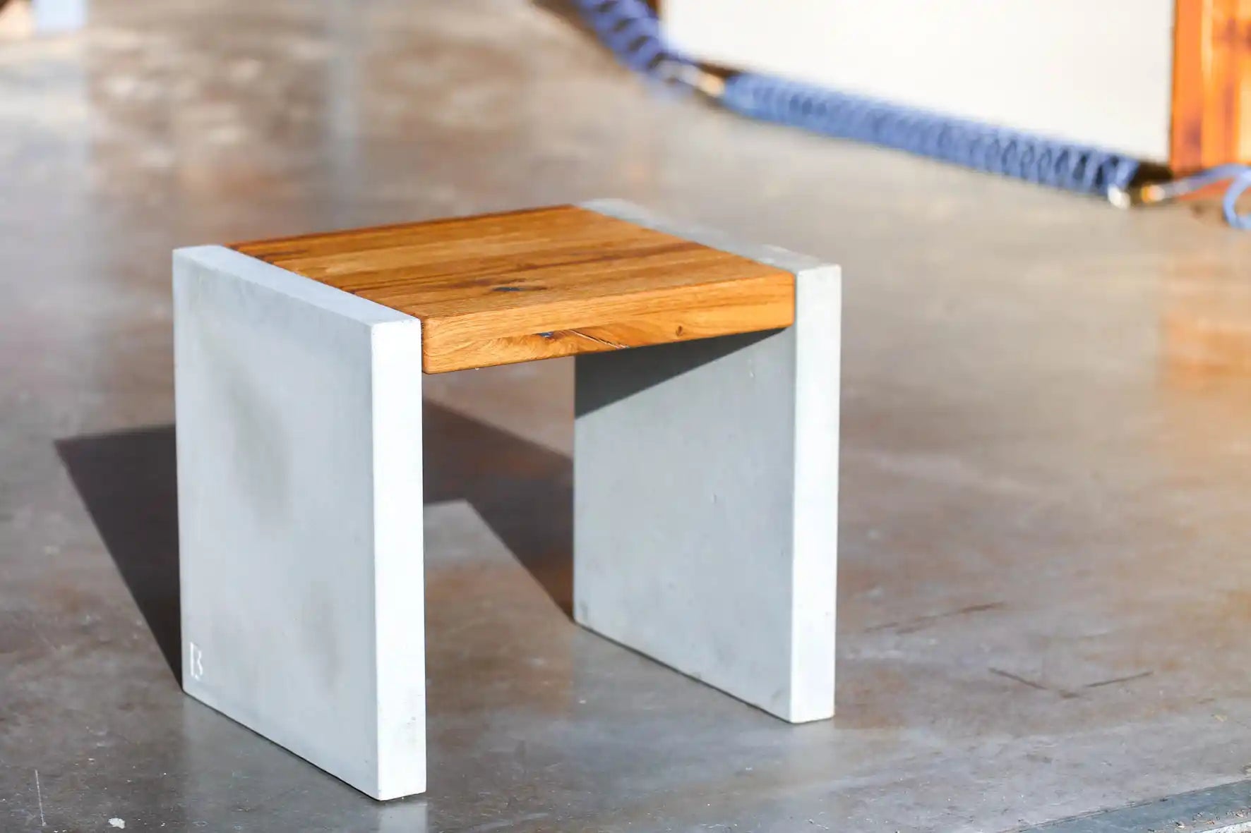 Hocker mit Sitzfläche aus Massivholz und Standfüßen aus Beton